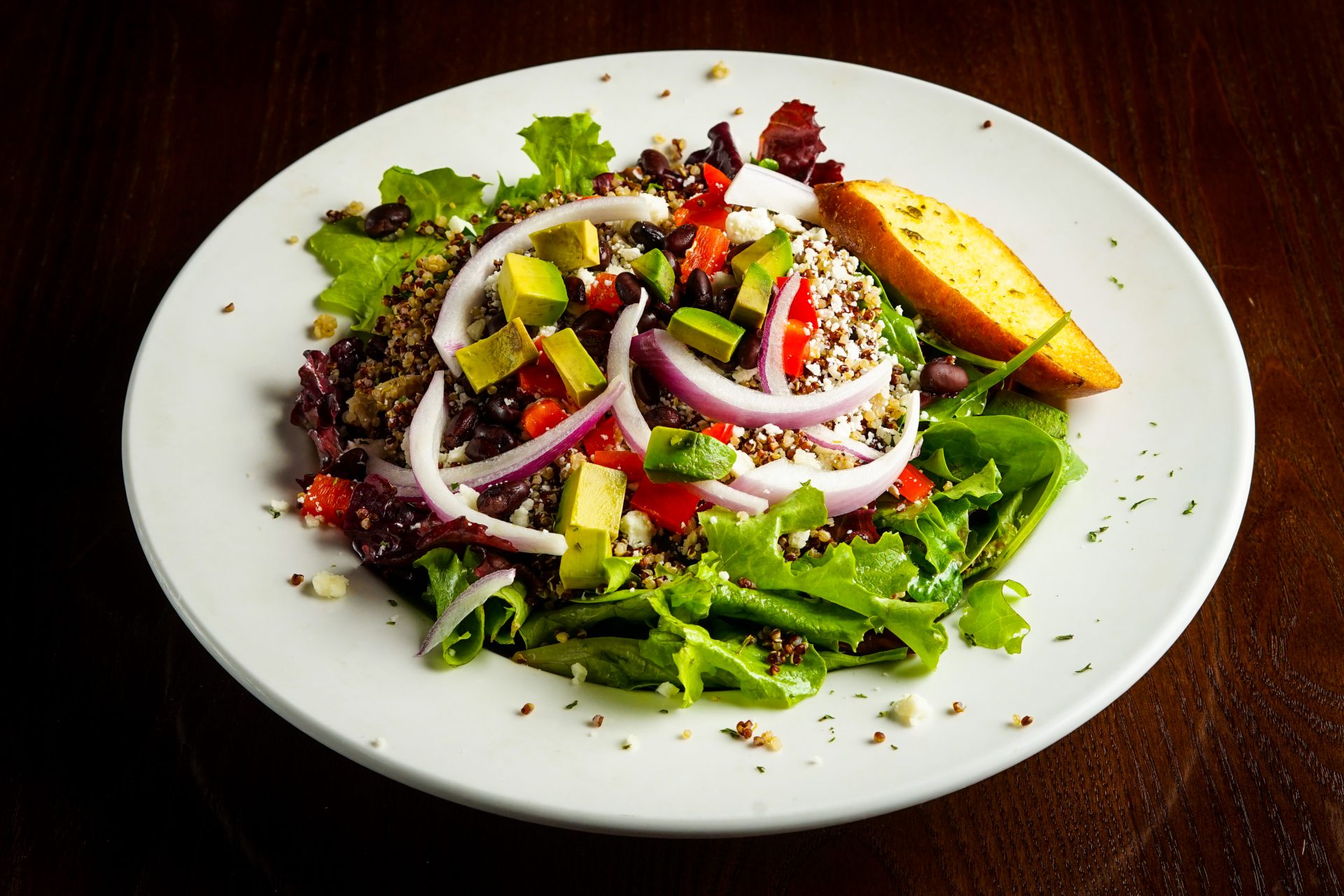 Image of Quinoa Salad - Red & White Quinoa, Mixed Greens, Avocado, Red Onion. Black Beans, Red Peppers, Queso Fresco, Champagne Vinaigrette