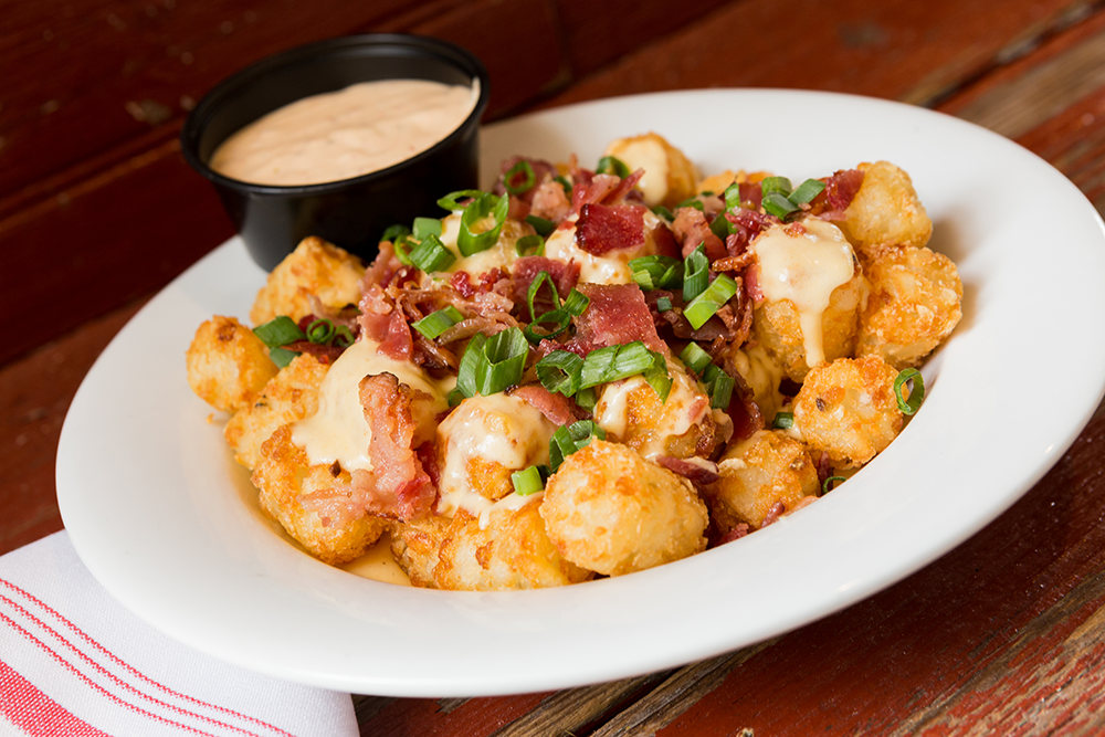 Image of Idaho Loaded Tots - Tater Tots, House Cheese Sauce, Scallion, Crumbled Bacon, Side of Spicy Ranch